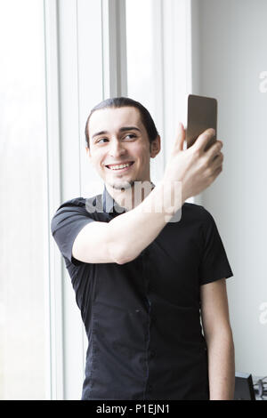 Ein junger Geschäftsmann, ein Foto mit einem Handy in einem modernen Büro. Stockfoto
