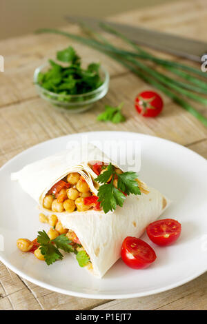 Burrito oder shawurma mit Kichererbsen, Tomaten und Petersilie auf eine leichte Platte. Selektive konzentrieren. Stockfoto