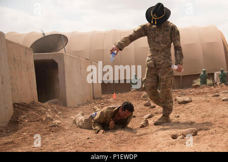 Us-Armee SPC. Joe Shelton gießt Wasser auf Sgt. 1. Klasse Samuel Amador, 1.BATAILLON, 124 Infanterie Regiment während er verbirgt sich ein Kabel nach der Befestigung ein Mock claymore Mine während einer Spur fahren Veranstaltung zur Unterstützung von Combined Joint Task Force - Horn von Afrika in einem nahe gelegenen Flugplatz in Dschibuti, Okt. 21, 2016. 21 acht US-Soldaten und eine Luftwaffe Flieger in der traditionellen Armee Ereignis, wo Sie 10 Aufgaben mit verschiedenen Veranstaltungen vor jeder Aufgabe in etwa 19 Stunden teilgenommen. Combined Joint Task Force-Horn von Afrika ist eine multinationale Anstrengung theater Sicherheit Zusammenarbeit zu leiten Stockfoto