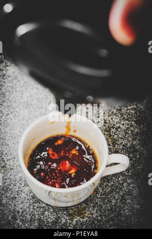 Gießen schwarzer Kaffee Nicht sanft in die Schale. Gießen Kaffee aus der Thermosflasche ohne Vorsicht, verschütten aus der Schale. Stockfoto