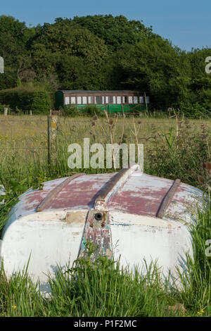 Ein umgedrehter alten hölzernen Boot vor einem Eisenbahnwaggon auf einer Hütte oder Ferienwohnung Chalet Home an thorness Bay konvertiert auf der Insel Wight. Stockfoto