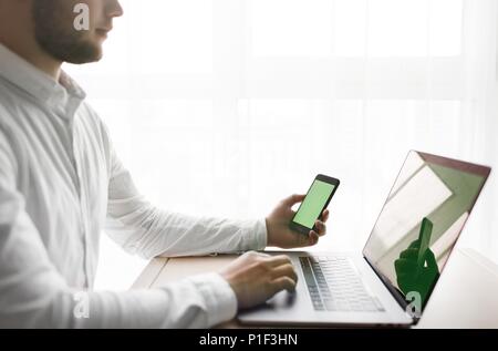 Junge lächelnde bärtigen Geschäftsmann arbeitet auf dem Computer Holding Stockfoto