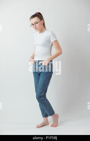 Clevere hipster Mädchen im weißen T-Shirt und Jeans in die Kamera schaut Stockfoto