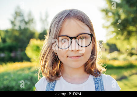 Mädchen mit Kamera und lächelnd in der Natur. Sommer Freizeitaktivitäten. Mädchen in der Brille mit schwarzem Rand. Stockfoto