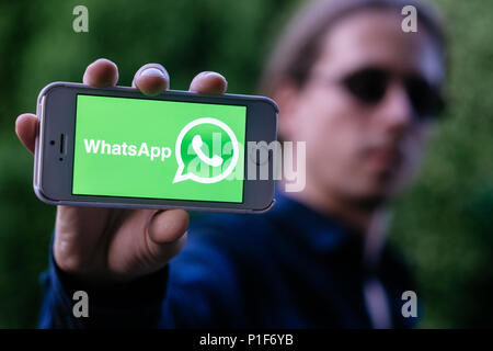 Nahaufnahme der coole junge Mann mit weißen iPhone mit WHATSAPP Logo auf dem Bildschirm Stockfoto