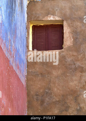 Die hellen, bunten Mauern des alten Hauses, in Rosa, Blau und Gelb Farben bemalt, wird ein kleines Fenster mit braunen Fensterläden. Stockfoto