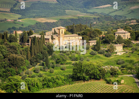 Häuser, Bäume und Felder im Val d'Orcia, Toskana, Italien umgeben. Im Jahr 2004 wird die Val d'Orcia wurde von der UNESCO in die Liste des Weltkulturerbes aufgenommen Stockfoto