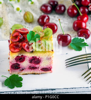 Käsekuchen mit Kirschen Beeren und hausgemachten Quark, mit Stachelbeere auf ein weißes Holzbrett eingerichtet Stockfoto