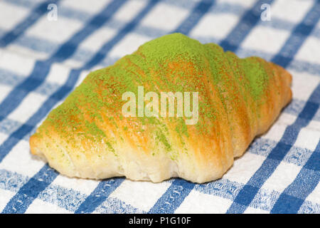 Frisches Matcha-Croissant auf einem blau karierten Tuch Stockfoto