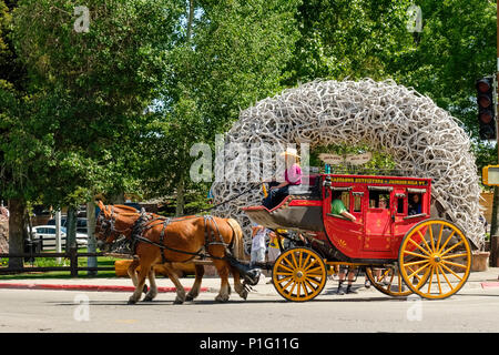 Pferdekutschen Stagecoach typisch für alte American West führt Touristen in Jackson, Wyoming vor iconic Park Eingang arch der Geweihe. Stockfoto