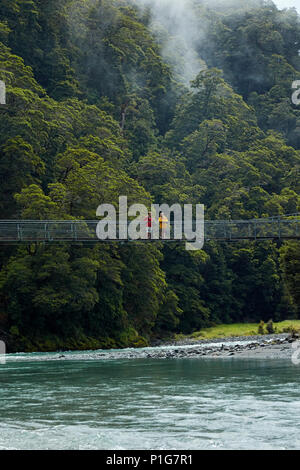 Touristen auf Fußgängerbrücke über Makarora River, Blue Pools, Mount Aspiring National Park, den Haast Pass, in der Nähe der Makarora, Otago, Südinsel, Neuseeland (mod. Stockfoto