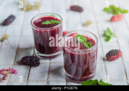 In der Nähe von Mulberry mulberry Saft und Obst, frische Beeren Obst und Beeren Smoothies mit Minze auf weißem Stoff. Stockfoto