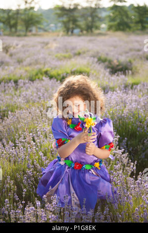 Glücklich lächelnde schöne kleine Mädchen in Fee lila Kleid und Zauberstab Stockfoto