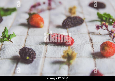 In der Nähe von Mulberry Obst und Erdbeeren, frische Beeren Obst und Minze auf weißem Stoff. Stockfoto