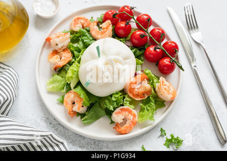Burrata Salat mit Garnelen, Salat, Tomaten und Olivenöl auf einem weißen Teller. Detailansicht. Gesunde Italienischer Salat Stockfoto