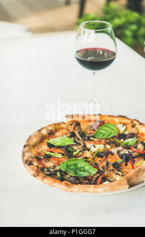 Frisch gebackene vegetarische Pizza und einem Glas Wein Stockfoto