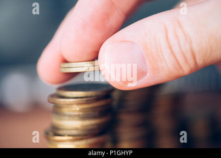 Nahaufnahme der männlichen Hand stapeln Münzen. Kosteneinsparungen und Budgetierung Konzept. Stockfoto