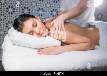 Junge Frau mit schwarzen Haaren ist immer entspannende Massage im Schönheitssalon Stockfoto
