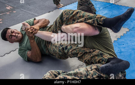 USS SOMERSET, Pazifischer Ozean (Okt. 2010) 28, 2016) - kpl. Jesus Diaz versucht, seine Gegner zu setzen, Cpl. Edward Chontos, in einem Arm bar während eines Marine Corps Martial Arts Program Training auf dem Wasser in den Pazifischen Ozean an Bord der USS Essex (LPD 25), Okt. 28, 2016. Marines Praxis MCMAP zu erhalten die höchste militärische Bereitschaft möglich, während sich im westlichen Pazifik eingesetzt. Diaz ist ein Tank Commander und Chontos ist ein Tank crewman; beide sind mit Tank Platoon, Bataillon Landung Team 1 Mrd., 4 Marines, 11 Marine Expeditionary Unit. (U.S. Marine Corps Foto von gunnery Sgt. R Stockfoto