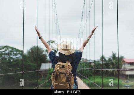 Traveler asiatische Frau erhobenen Arme zum Himmel am Fuß der Brücke über den Fluss, auf dem Land, Ferien Sommerferien reisen Stockfoto