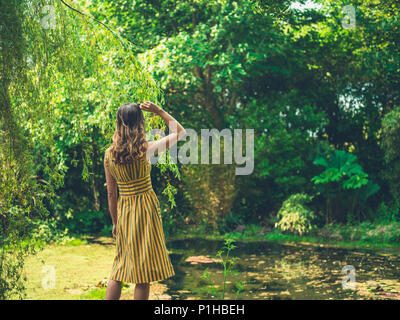 Eine modische Frau trägt ein Kleid steht ein Teich in einem Garten Stockfoto
