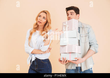 Portrait von Naughty umgekippt Frau Ablehnung aller derzeitigen Boxen, die brunette Mann hält in der Hand über beigen Hintergrund isoliert Stockfoto
