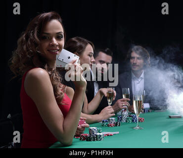 Junge brünette Frau Poker spielen auf schwarzem Hintergrund Stockfoto