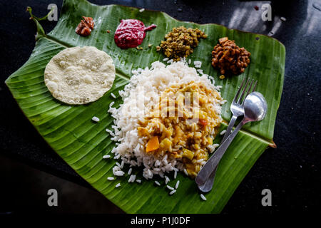 Sadya, die Kerala Version von "thali", einem typischen South India Essen von Reis, Sambar (Linsen Eintopf), Chutneys und Pickles auf einem Bananenblatt serviert. Stockfoto