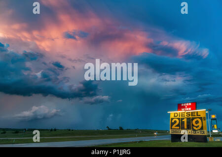 Gewitter (Cumulonimbus capillatus Mammatus) nach Sonnenuntergang während der Blauen Stunde mit Tankstelle in Texas, USA Stockfoto