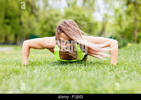 Schöne Frau, Push-ups das grüne Gras im Park ob. Stockfoto