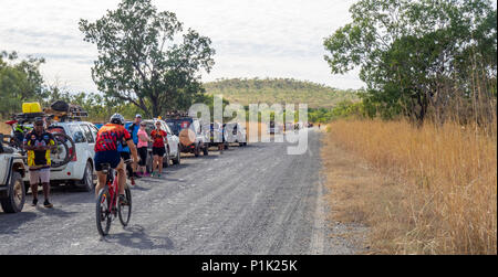 Gibb Herausforderung 2018 Radfahrer in Jersey und Bib vorbei Konvoi von 4 wheel drive Support Fahrzeuge auf unbefestigten Straße der Gibb River Road Kimberley WA Australien Stockfoto