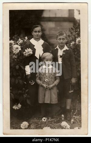 DEUTSCHLAND - UM 1940s: Vintage-Foto zeigt junge Frau mit Kindern (Junge und Mädchen) im Garten posieren. Schwarze & weiße antike Fotografie. 1940s. Stockfoto