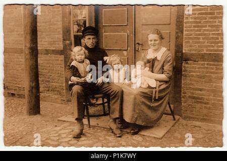 DEUTSCHLAND - UM 1930s: Das Vintage-Foto zeigt, dass die ländliche Familie vor dem Haus sitzt. Schwarze & weiße antike Fotografie. 1930s Stockfoto