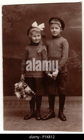 PRAG, TSCHECHOSLOWAKISCHE REPUBLIK - 4. FEBRUAR 1930: Vintage-Foto zeigt Mädchen und Jungen (Geschwister), Mädchen trägt weißes Haarband. Schwarzweiß-Studiofotografie. 1930s. Stockfoto