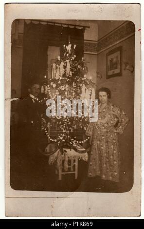 DIE TSCHECHOSLOWAKISCHE REPUBLIK - UM 1923: Ein altes Foto zeigt ein älteres Paar neben dem Weihnachtsbaum. Schwarz-Weiß-Antiquitätenfoto. 1930s Stockfoto