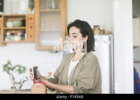 Frau gießen frischen Kaffeebohnen in eine Kaffeemühle Stockfoto