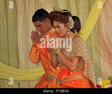 Eine buddhistische Paar, in schöne Hochzeit Kleidung, Knien während ihrer Hochzeit Zeremonie, die Hände in einer Geste des Gebets und Dank. Stockfoto