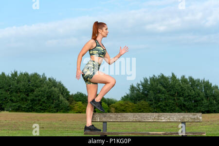Sportlerin, 'Step Up' auf einer Parkbank Stockfoto