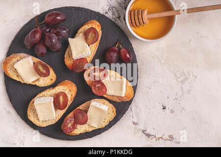 Schale mit Sandwiches, Käse, Trauben und Honig. Ansicht von oben. Stockfoto