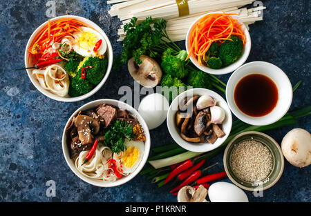 Zutaten der asiatischen Küche Udon-nudeln Schüssel Eier Gemüse Gewürze Sojasauce Kräuter. Flach Top View Stockfoto