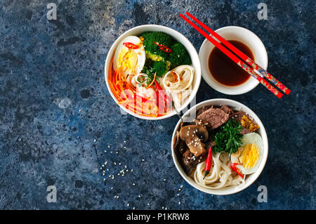 Zwei variation Udon-nudeln Schalen. mit Brokkoli, ed, Karotten, Gewürze und Fleisch, Pilzen, Ei und Petersilie. Ansicht von oben. Stockfoto