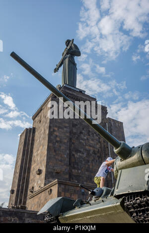 Yerevan, Armenien - 20. August 2017: Kinder spielen auf dem Tank mit Mutter Armenien Denkmal hinter, im Park des Sieges in Eriwan. Stockfoto