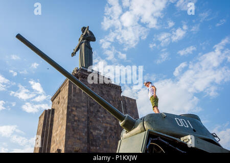 Yerevan, Armenien - 20. August 2017: Kinder spielen auf dem Tank mit Mutter Armenien Denkmal hinter, im Park des Sieges in Eriwan. Stockfoto