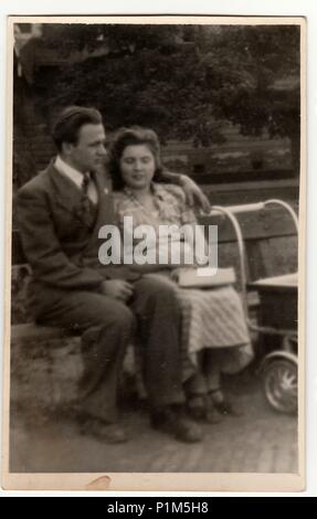 Italien - ca. 1940 s: Vintage Foto zeigt ein junges Paar mit Kinderwagen. Paar sitzt auf einer Bank im Stadtpark. Schwarz & Weiß antike phtography. Stockfoto