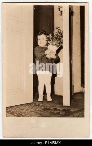 Die tschechoslowakische Republik - circa 1950s: Vintage Foto zeigt ein niedliches kleines Mädchen hält die Vase mit Blumen. Retro Fotografie. Stockfoto