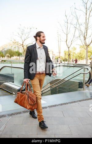 Volle Länge Bild von Erwachsenen Geschäftsmann im stilvollen Gesellschaftsmode Aufstehen aus der U-Bahn und zu Fuß mit Leder männliche Tasche und Zeitung in der Hand Stockfoto