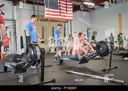 Weibliche oder Frau in einer CrossFit Fitness Challenge Wettbewerb mit einem Rudergerät bis zur Erschöpfung in einem Fitnessstudio in Montgomery Alabama, USA konkurrieren. Stockfoto