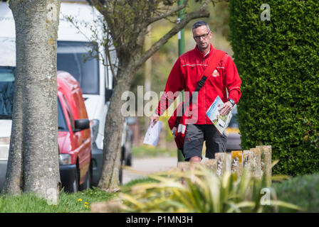 Royal Mail Postbote wandern die Buchstaben für die Lieferung in England, Großbritannien. Stockfoto