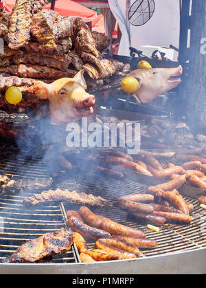 Würstchen, Schweinerippchen und andere Fleischsorten Schnitte auf Holzkohle Grill in einem Stall eines Street Food Fair. Stockfoto