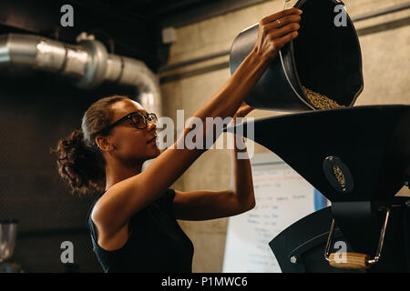 Frau die Kaffeebohnen in der Kaffeerösterei Maschine Stockfoto